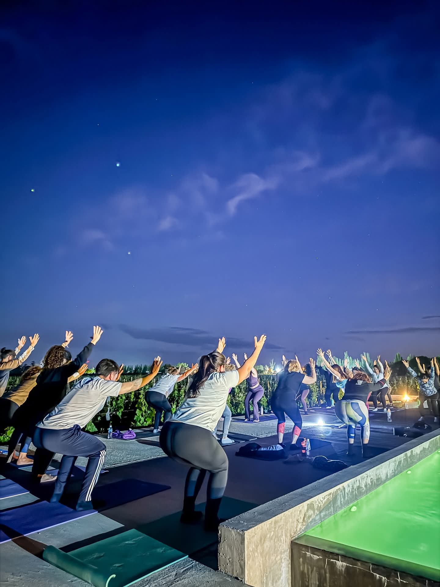 Clase nocturna de Power Yoga junto a la piscina bajo el cielo estrellado
