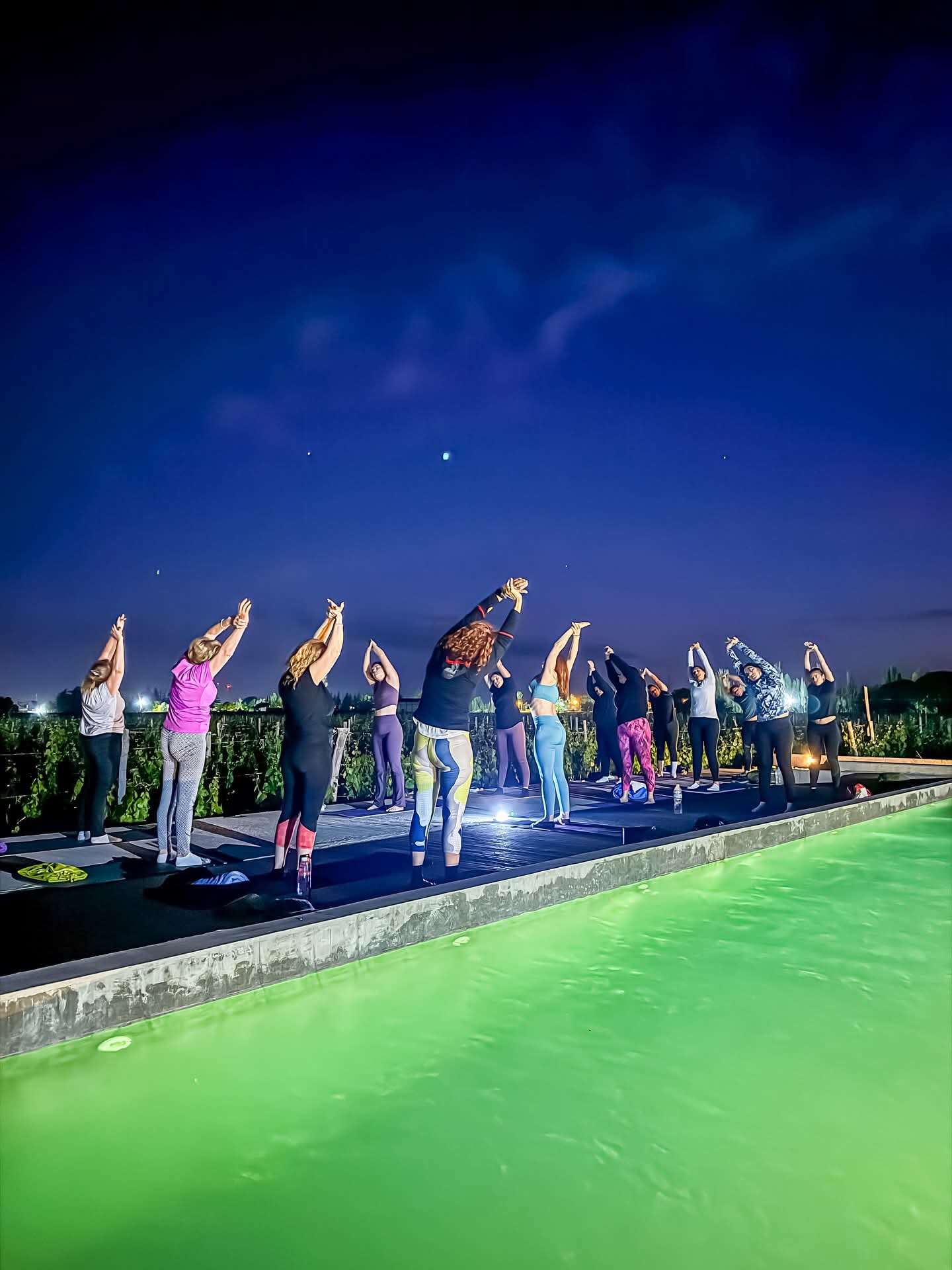 Clase de yoga al aire libre en estiramiento lateral junto a la piscina